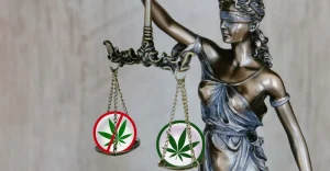 Marihuana a legislatíva - ilustračný obrázok: bronzová socha predstavujúca slepú spravodlivosť drží v ruke váhy, na ktorých sú symboly zákazu a povolenia marihuany