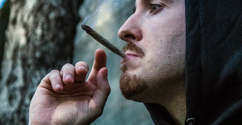 mladý muž fajčí jointa z marihuany