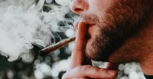 Detail: mladý muž s bradou fajčí jointa