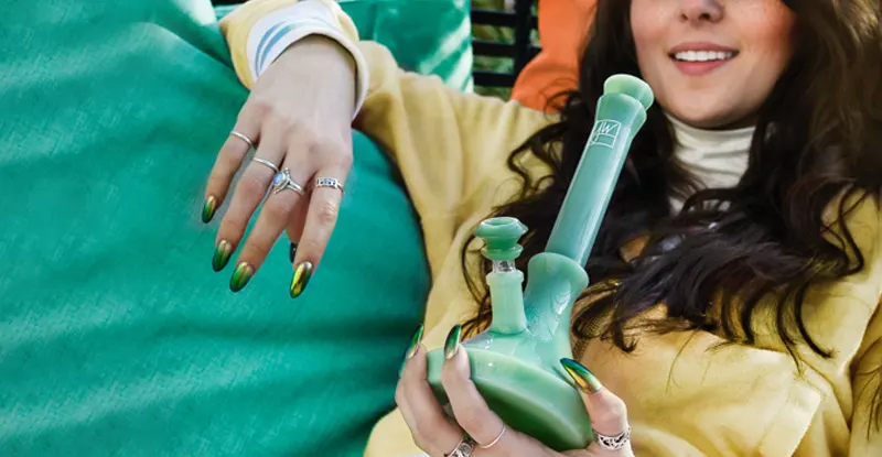 Detail zeleného skleneného bonga, ktoré drží v rukách mladá usmievajúca sa žena
