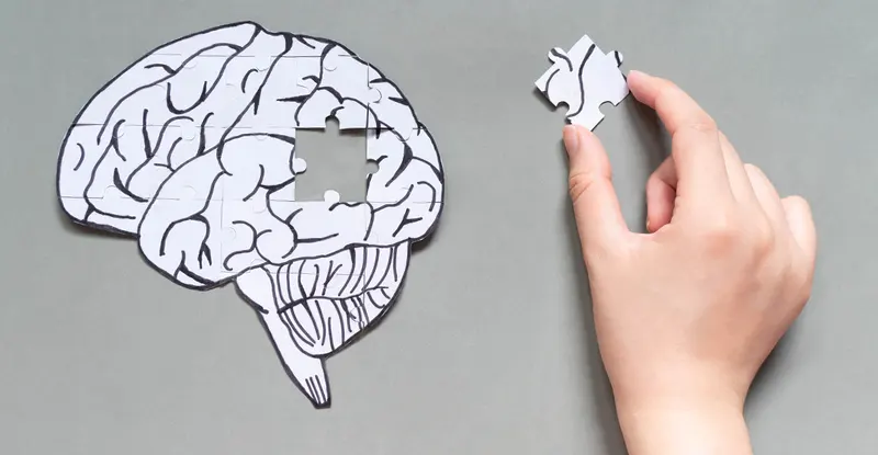 Ilustračný obrázok - pamäť: ruka skladá puzzle v tvare ľudského mozgu