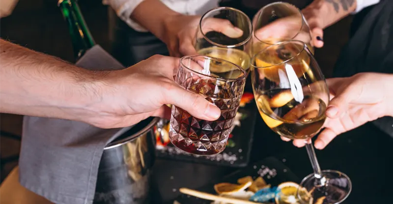 Alkohol: detail pripíjania si s troma pohármi vína a jedným pohárom silnejšieho alkoholu