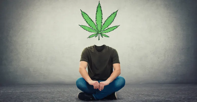 Ilustračný obrázok: závislosť na marihuane - muž sedí na zemi a namiesto hlavy má štylizovaný konopný list